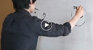 The artist draws two portraits at the same time with both hands